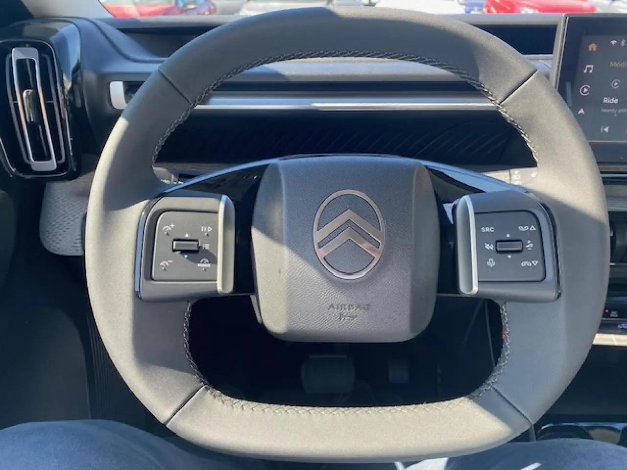 Gros plan sur le volant multifonctions gris du Citroën C3 Aircross 2026 avec commandes intégrées et logo central.