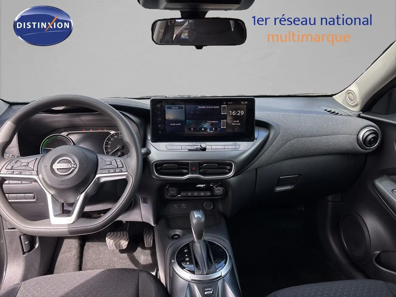 Vue intérieure côté conducteur du Nissan Juke Hybrid 2024, avec tableau de bord moderne et sièges tissu noir.