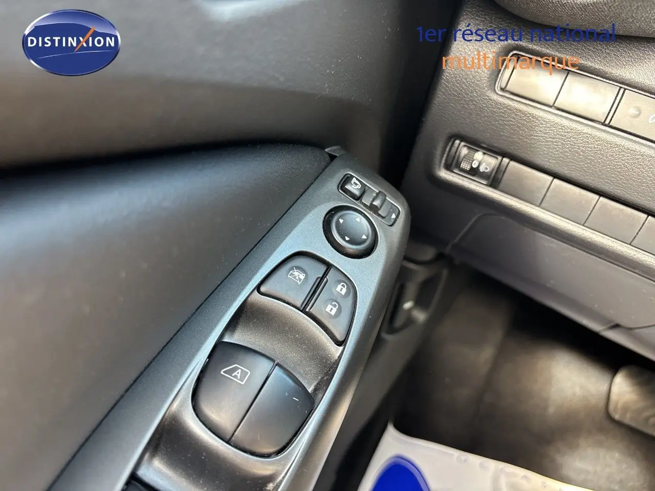 Gros plan sur les commandes de vitres et rétroviseurs côté gauche du Nissan Juke Hybrid gris squale métal 2024.