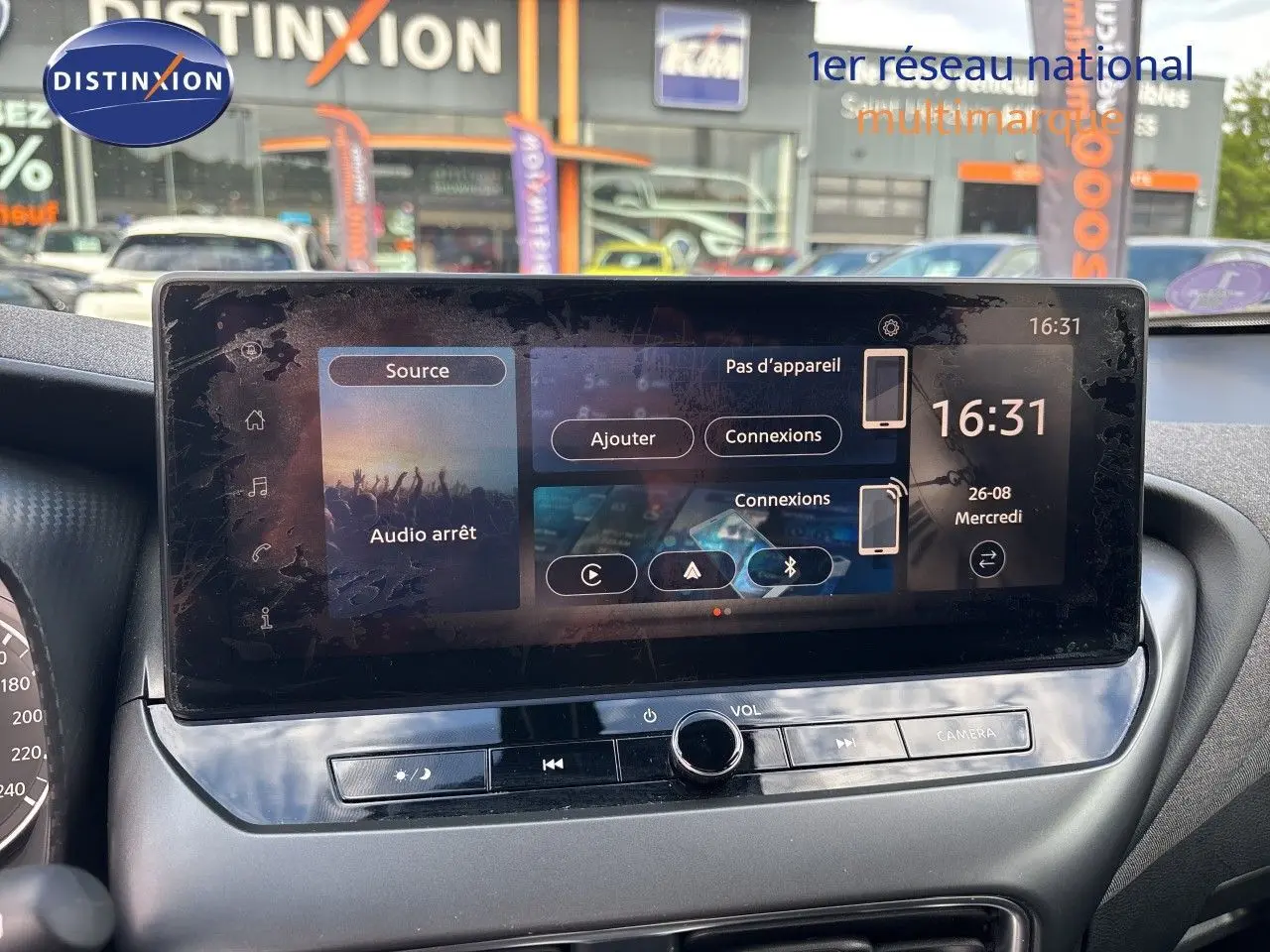 Écran tactile central du Nissan Juke Hybrid 2024 en intérieur, avec commandes audio et caméra visibles.