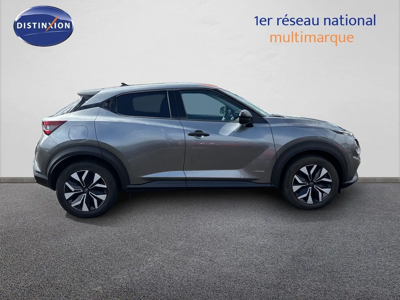 Vue de profil côté gauche du Nissan Juke Hybrid 143ch Business Edition gris squale metal avec jantes noires et détails noirs.