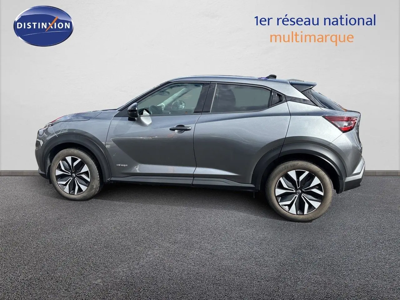 Nissan Juke Hybrid gris squale metal, vue 3/4 arrière droit, avec jantes alliage et vitres teintées.