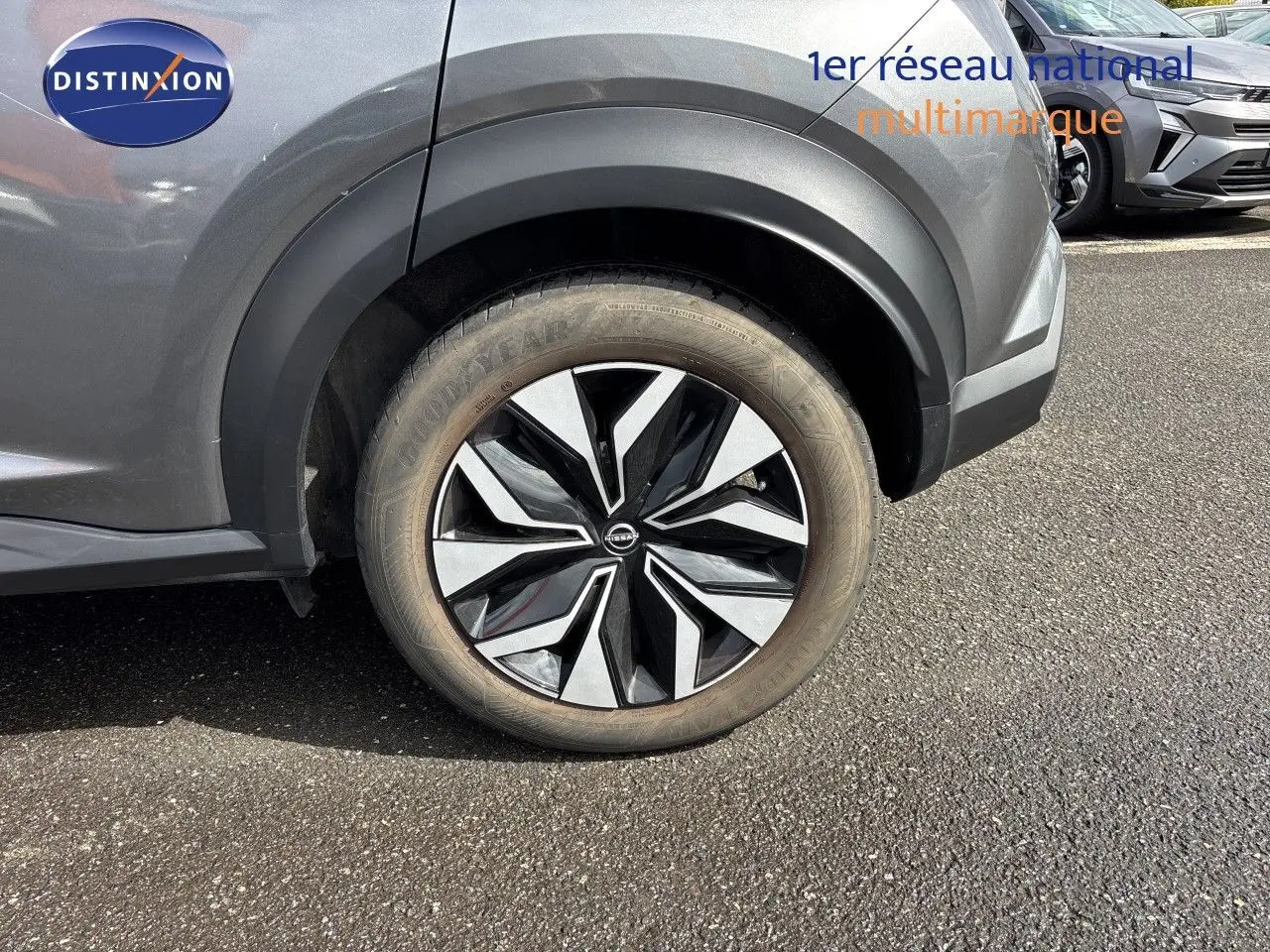 Gros plan sur la roue avant gauche du Nissan Juke gris squale métal, mettant en valeur la jante noire et argentée au design moderne.