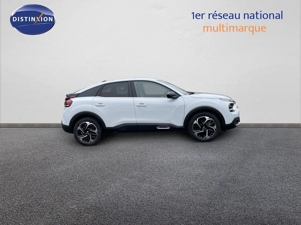 Profil côté droit d'une Citroën C4 2024 blanc métal avec jantes noires et détails noirs contrastants.