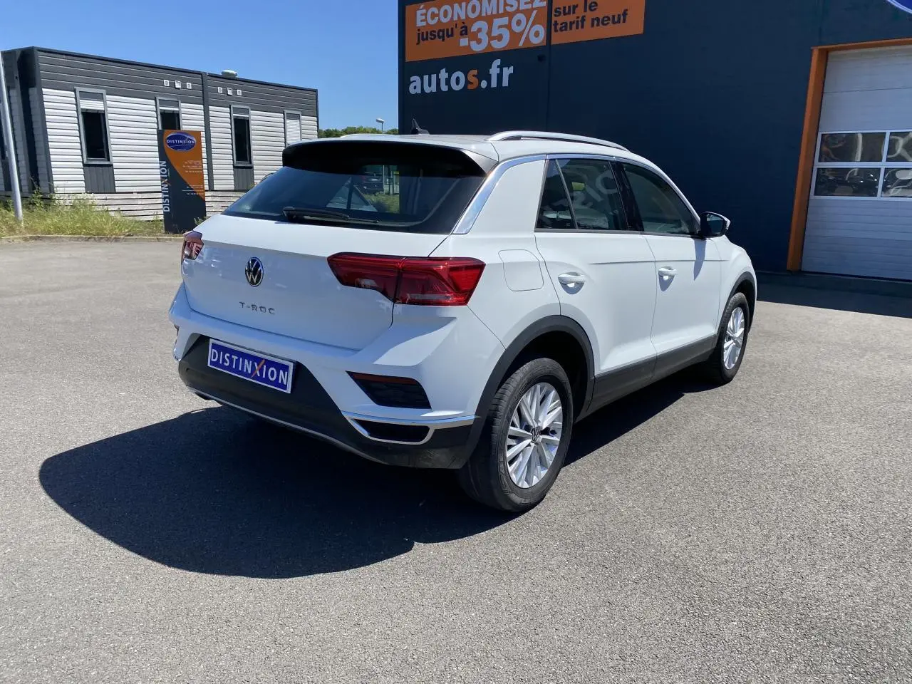 Volkswagen T-Roc blanc pur vu de trois quarts arrière droit sur parking devant bâtiment autos.fr