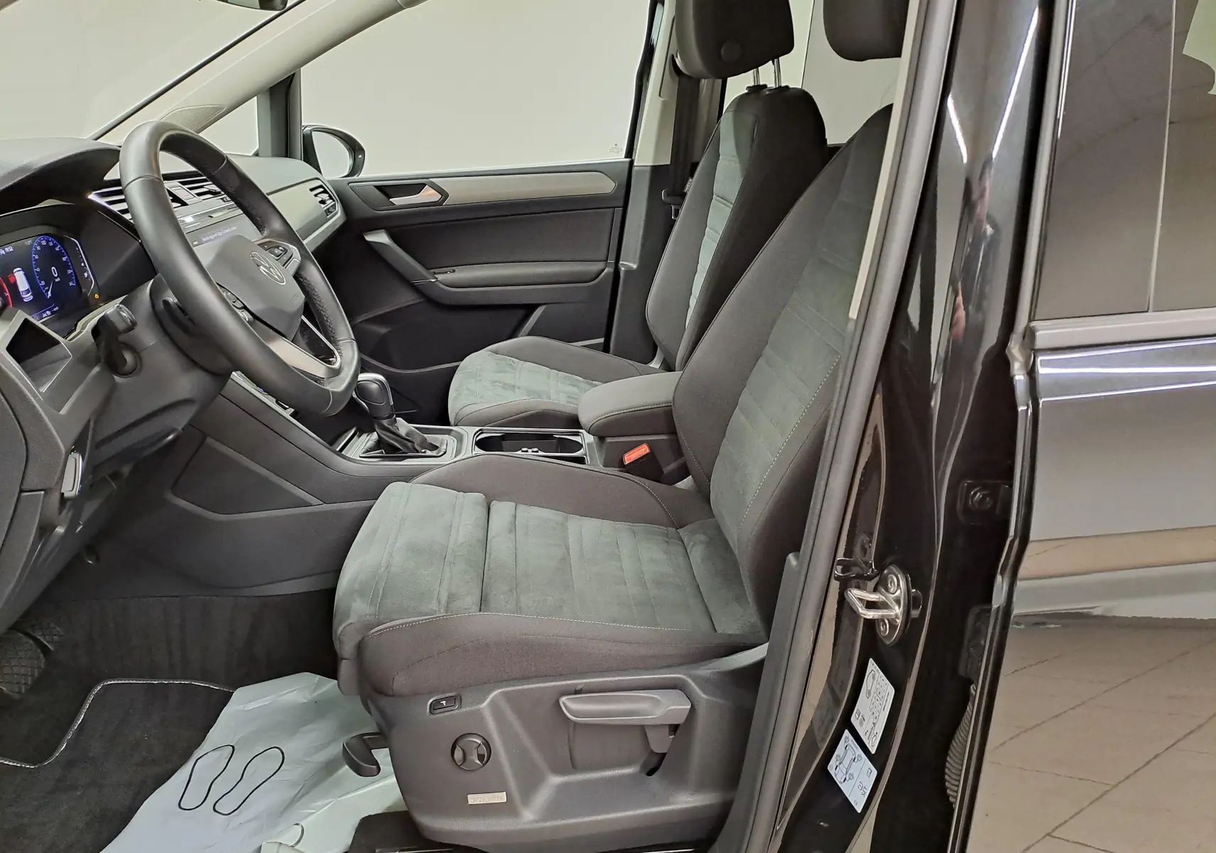 Intérieur côté conducteur du Volkswagen Touran 2025 noir Grenadille, sièges avant en Alcantara avec réglages ergonomiques.
