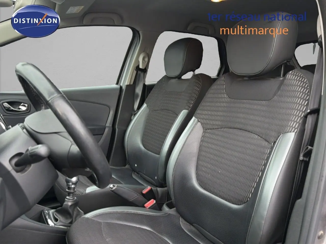 Vue intérieure côté gauche montrant les sièges avant en tissu et cuir gris du Renault Captur 2016 avec volant et levier de vitesse.