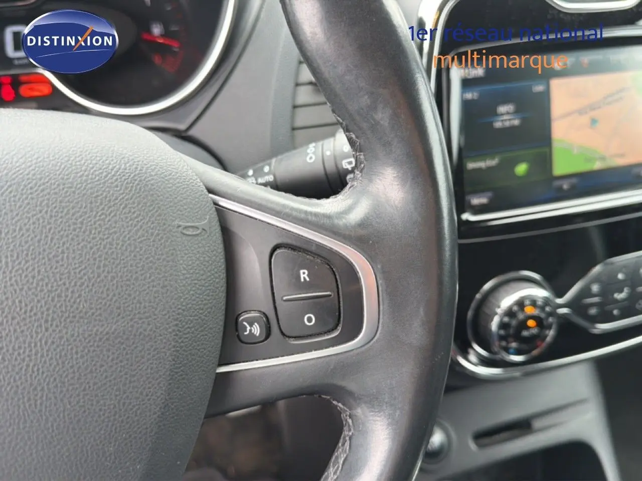 Gros plan sur le volant en cuir noir du Renault Captur 2016 avec commandes intégrées, tableau de bord et écran tactile en arrière-plan.