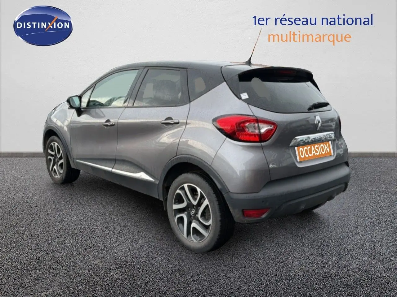 Renault Captur gris Cassiopée avec toit noir, vue 3/4 arrière droit, jantes alliage et feux arrière visibles.