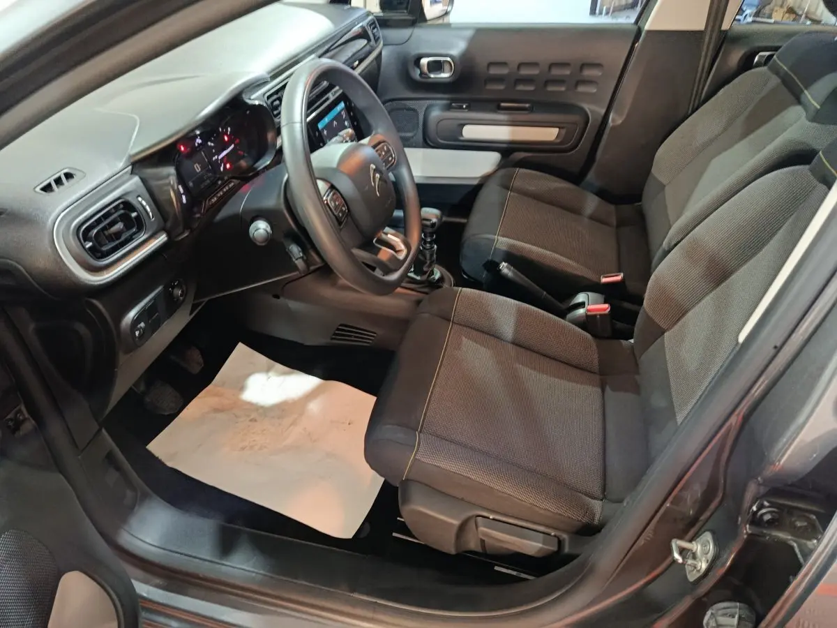 Intérieur avant droit de la Citroën C3 gris foncé 2024, avec tableau de bord et sièges tissu noirs.