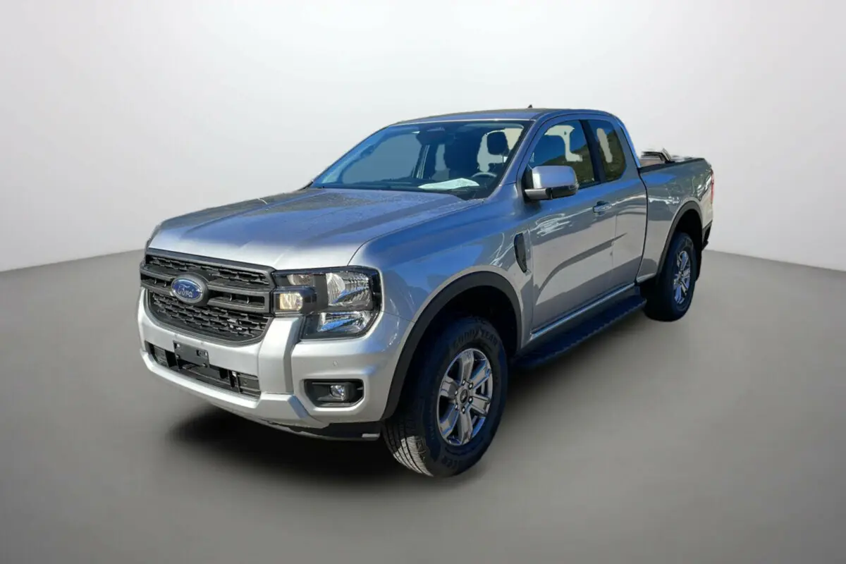 Ford Ranger gris iconic en 3/4 avant droit avec rideau coulissant sur la benne et marchepieds noirs.