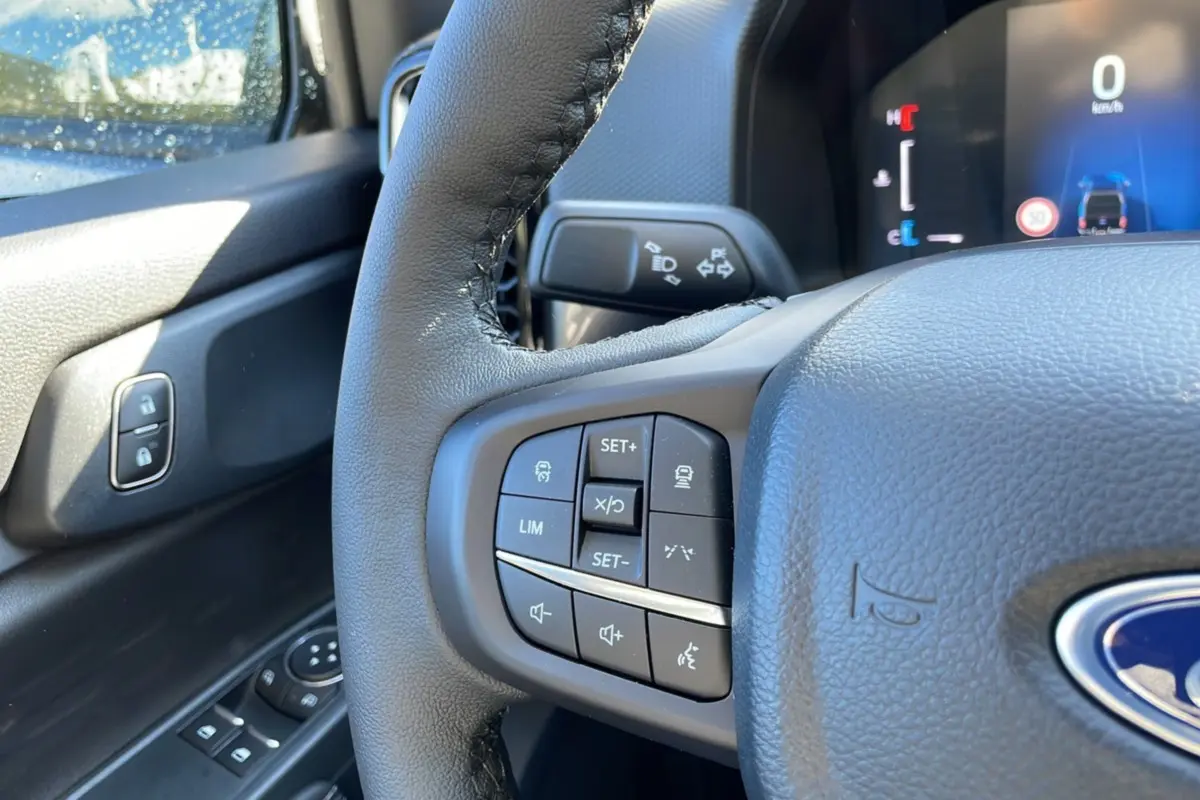 Gros plan sur le volant cuir multifonctions côté gauche du Ford Ranger gris, avec commandes de régulateur et limiteur.