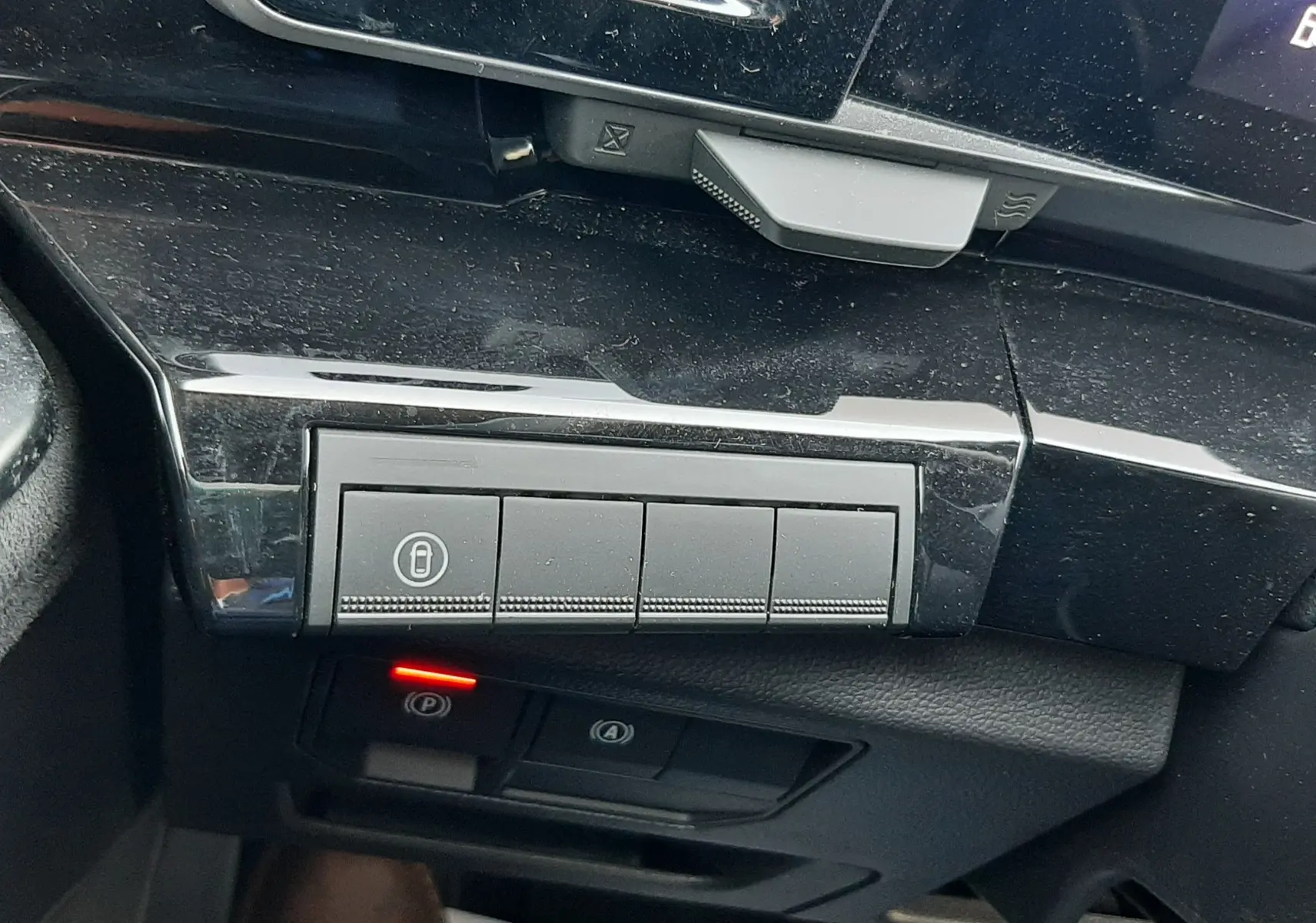 Gros plan sur les commandes noires du tableau de bord côté gauche du Renault Austral E-Tech hybride 2025, avec témoin rouge allumé.