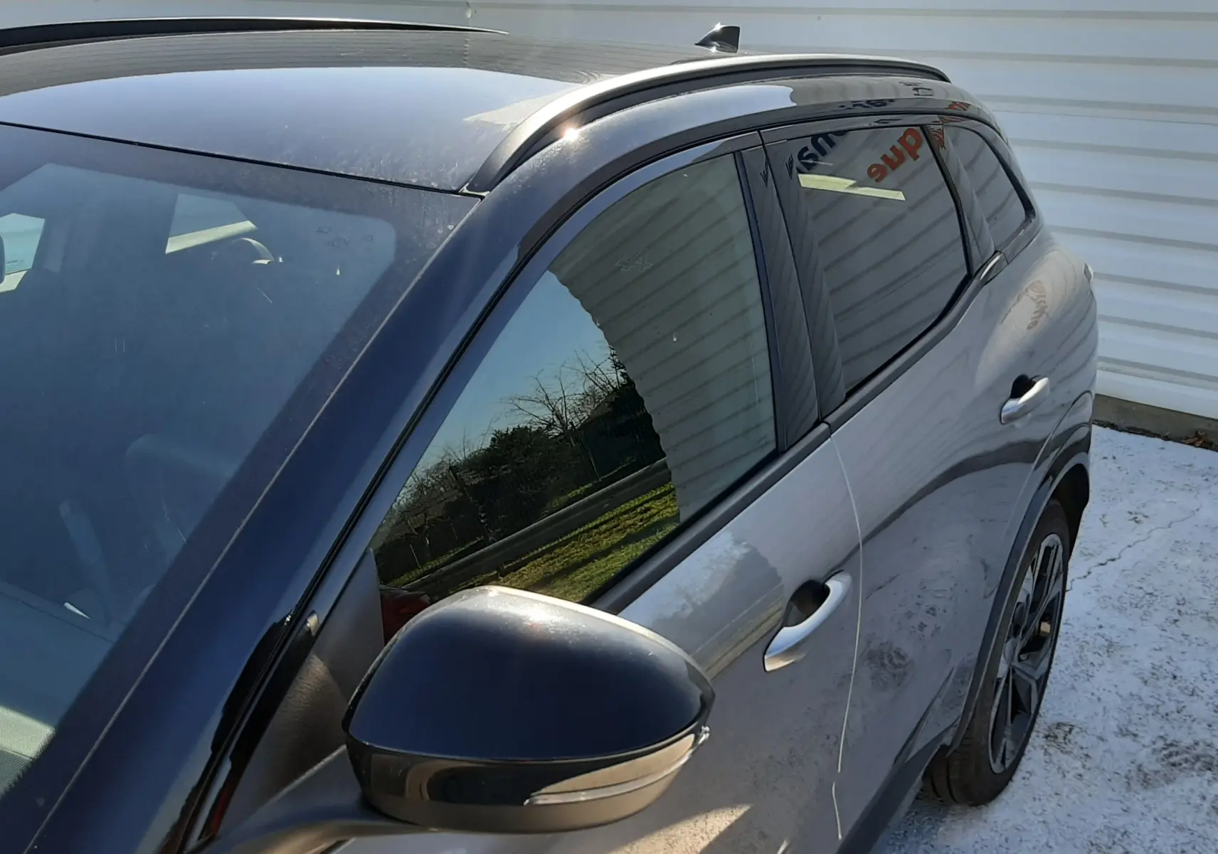 Vue de côté droit avant d'un Renault Austral gris schiste avec toit noir et rétroviseur noir brillant.