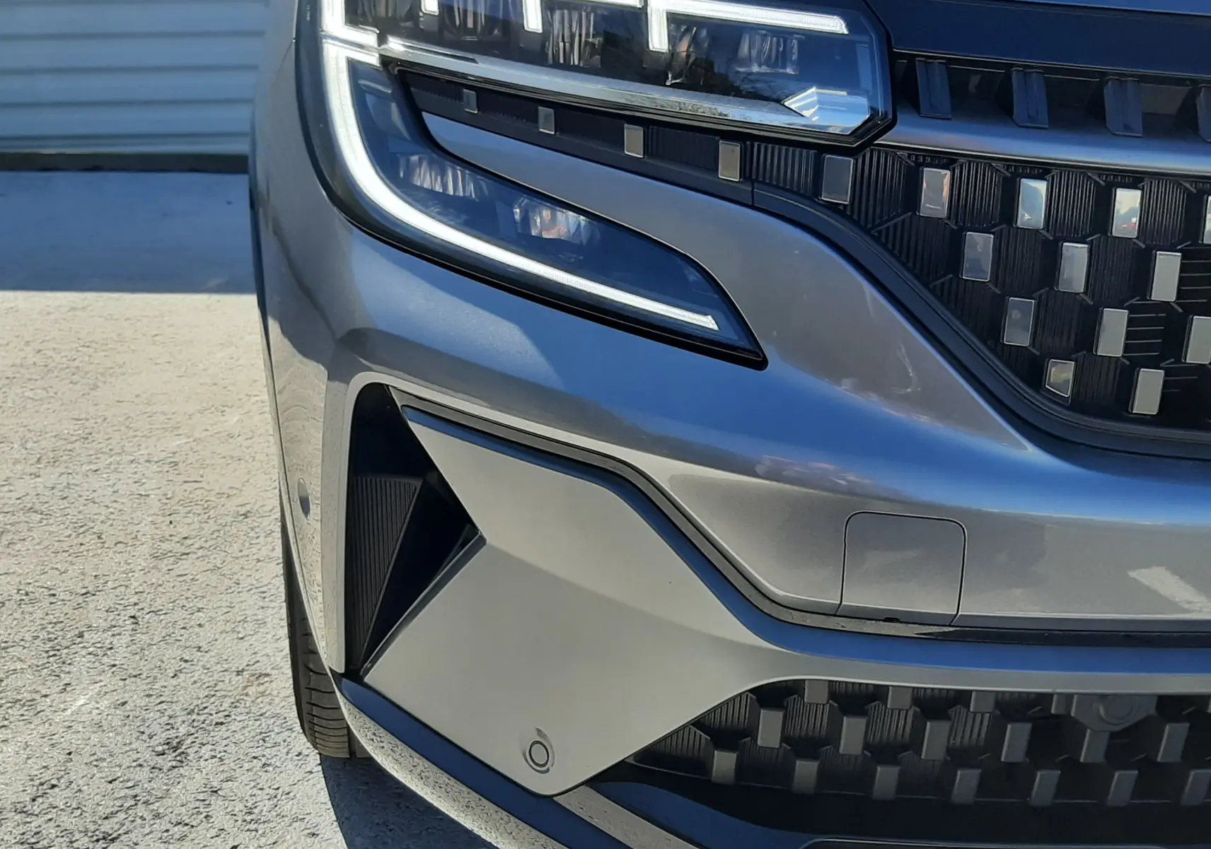 Gros plan sur l'avant gauche du Renault Austral gris schiste avec éclairage LED et calandre noire texturée.