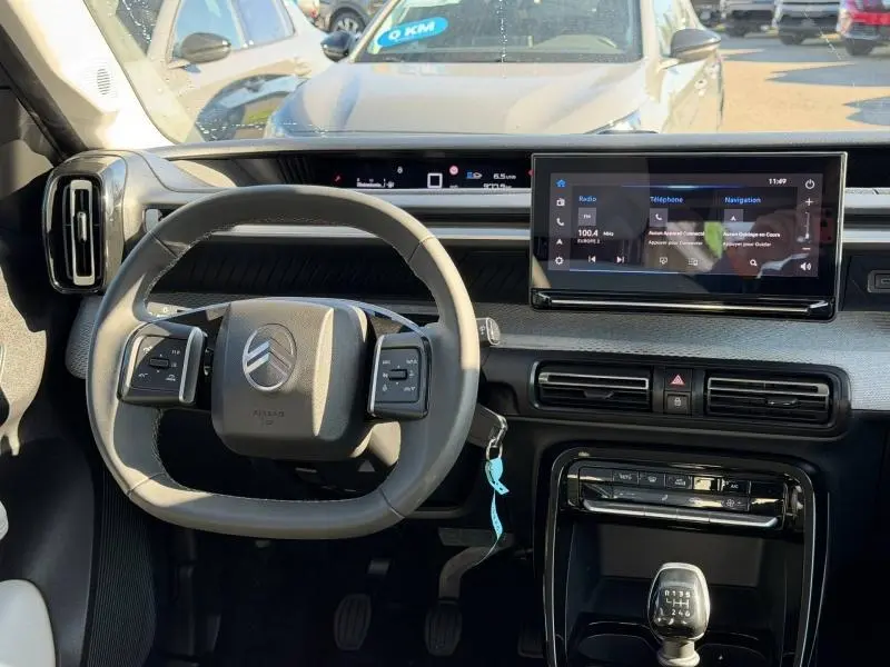 Vue intérieure du tableau de bord de la Citroën C3 2025, avec volant multifonctions et écran tactile central.