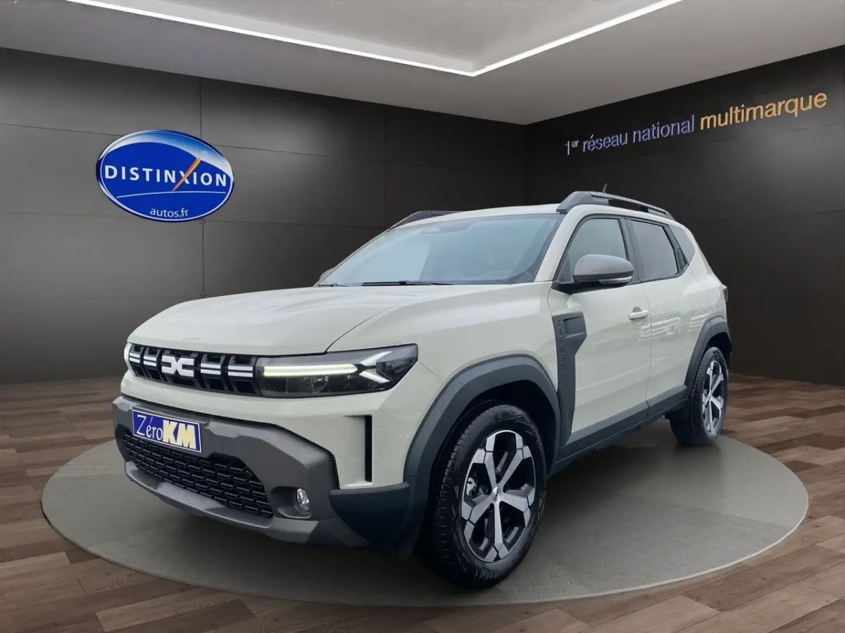 Dacia Duster beige en 3/4 avant droit, avec calandre distinctive et jantes alliage bicolores.