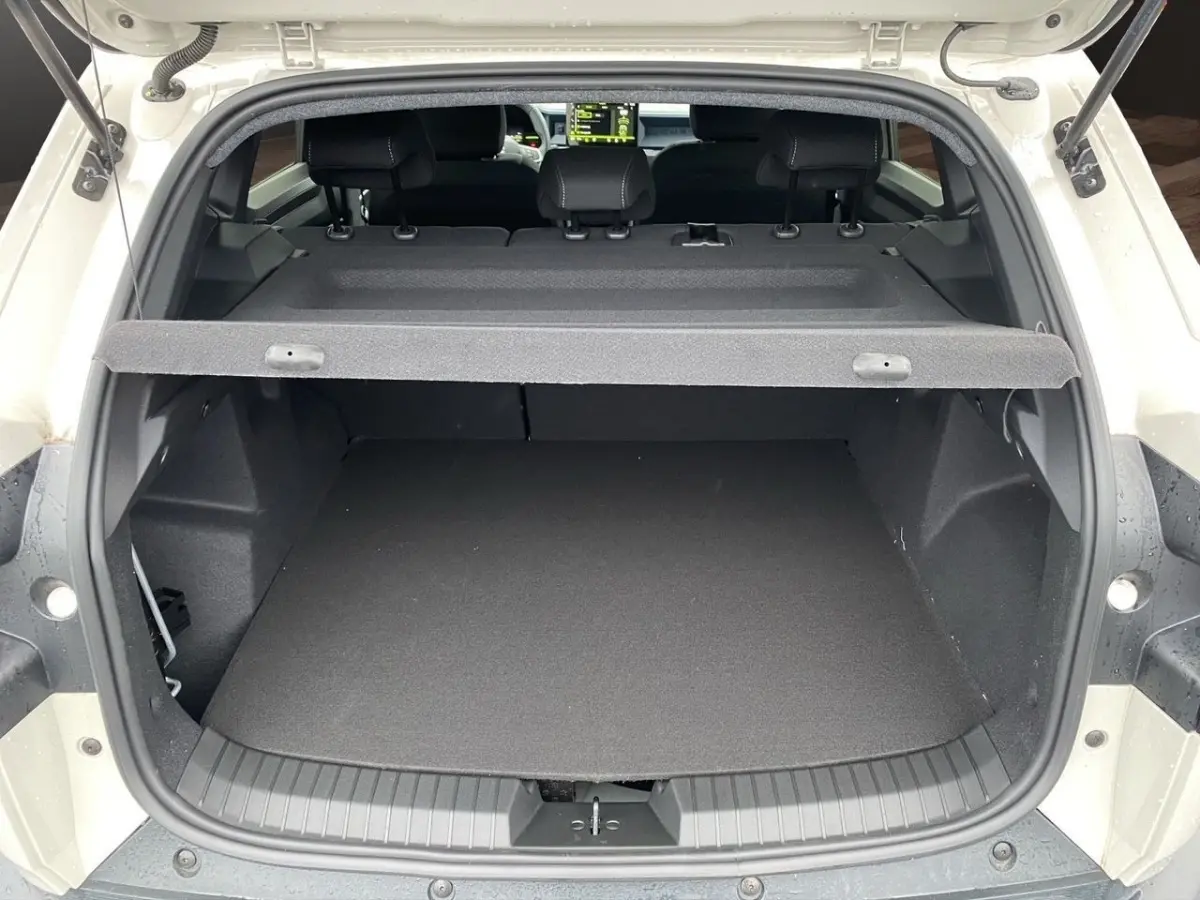 Coffre ouvert vu de l'arrière d'un Dacia Duster beige 2025, avec tablette de coffre et banquette arrière visible.