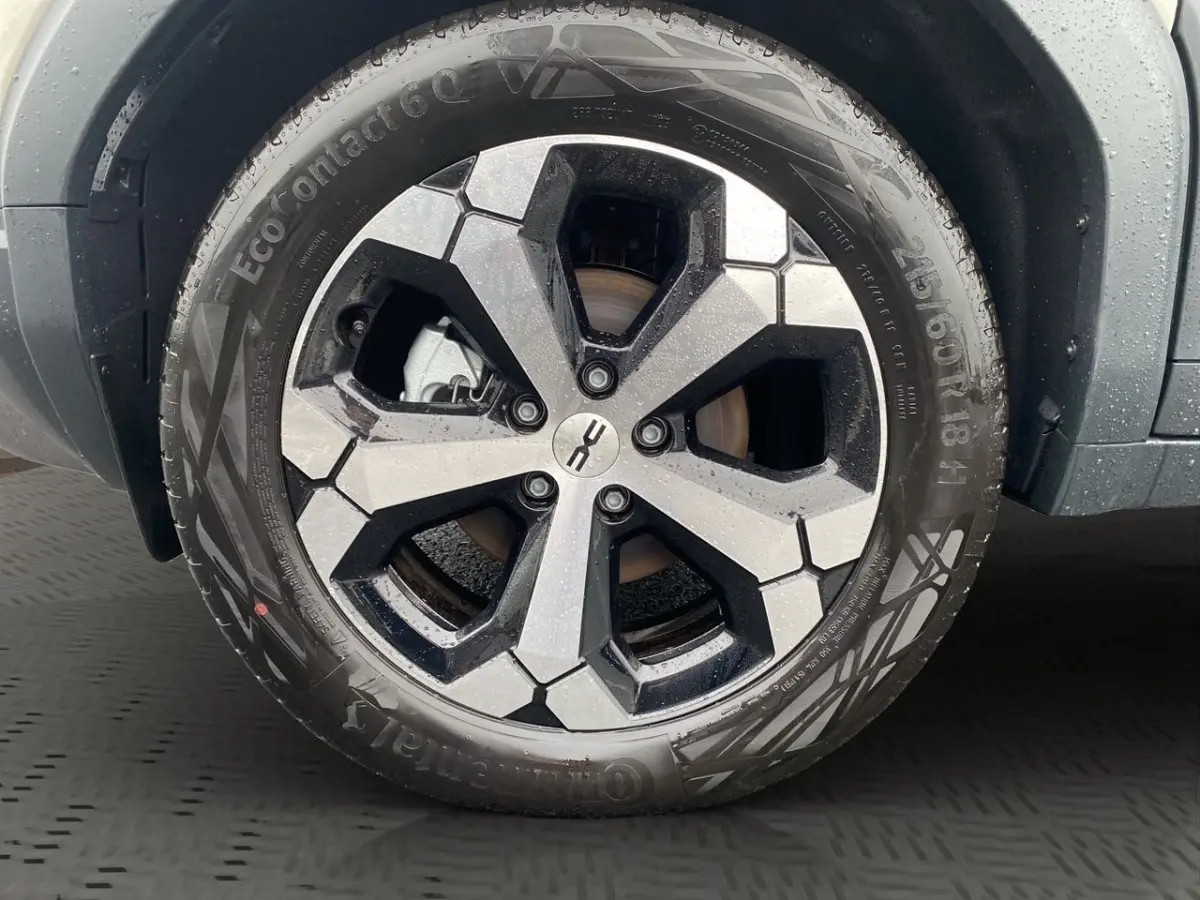 Gros plan sur la jante noire et argentée d’un Dacia Duster beige, avec pneu Continental sous la pluie.