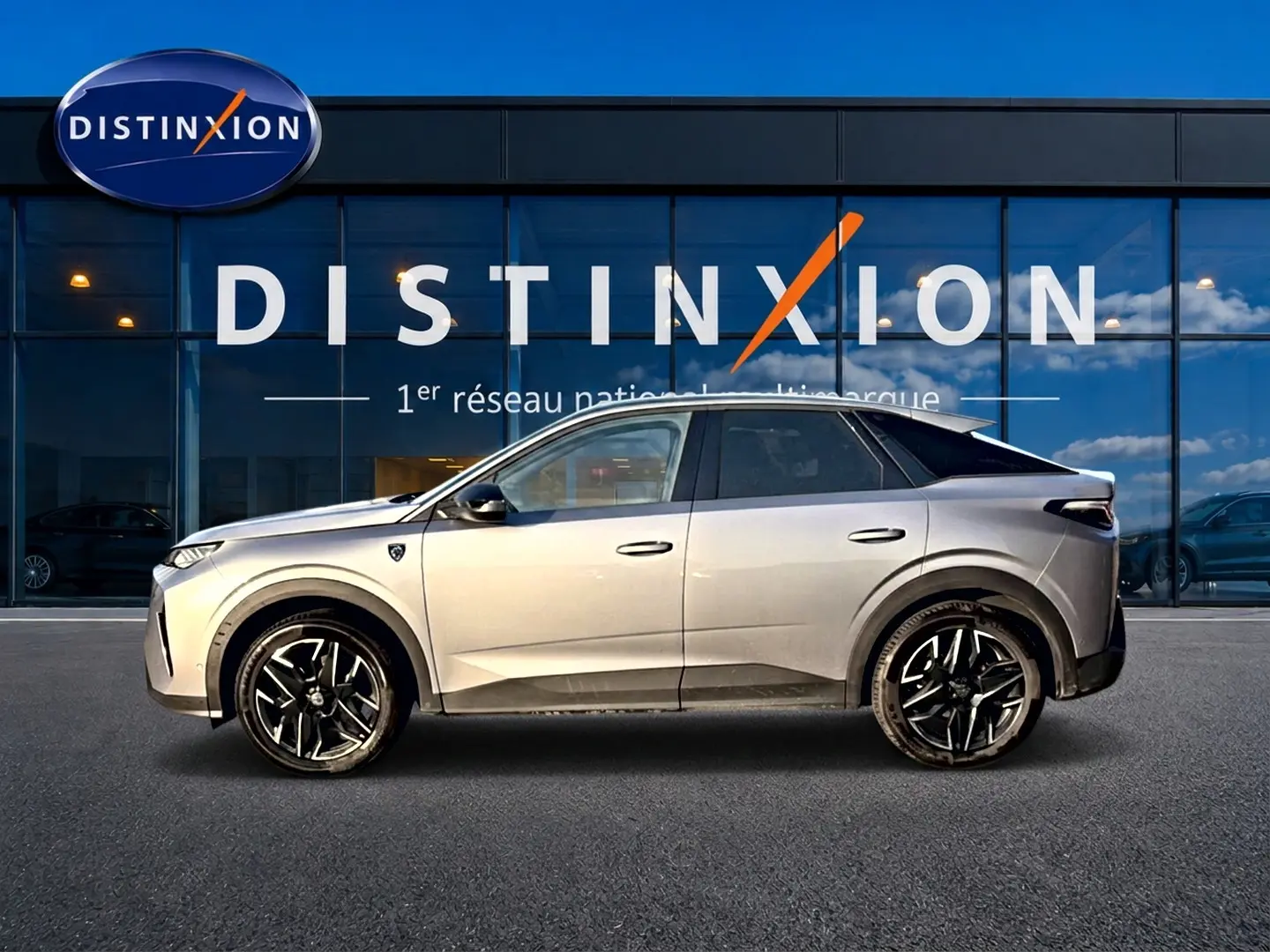 Vue de profil droit du Peugeot 3008 gris 2025 avec jantes alliage noires devant une vitrine Distinxion.