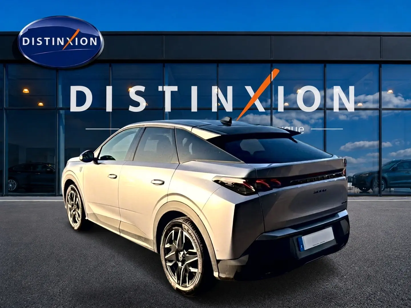 Vue 3/4 arrière droite du Peugeot 3008 gris 2025 avec jantes alu et feux arrière LED, devant une vitrine Distinxion.