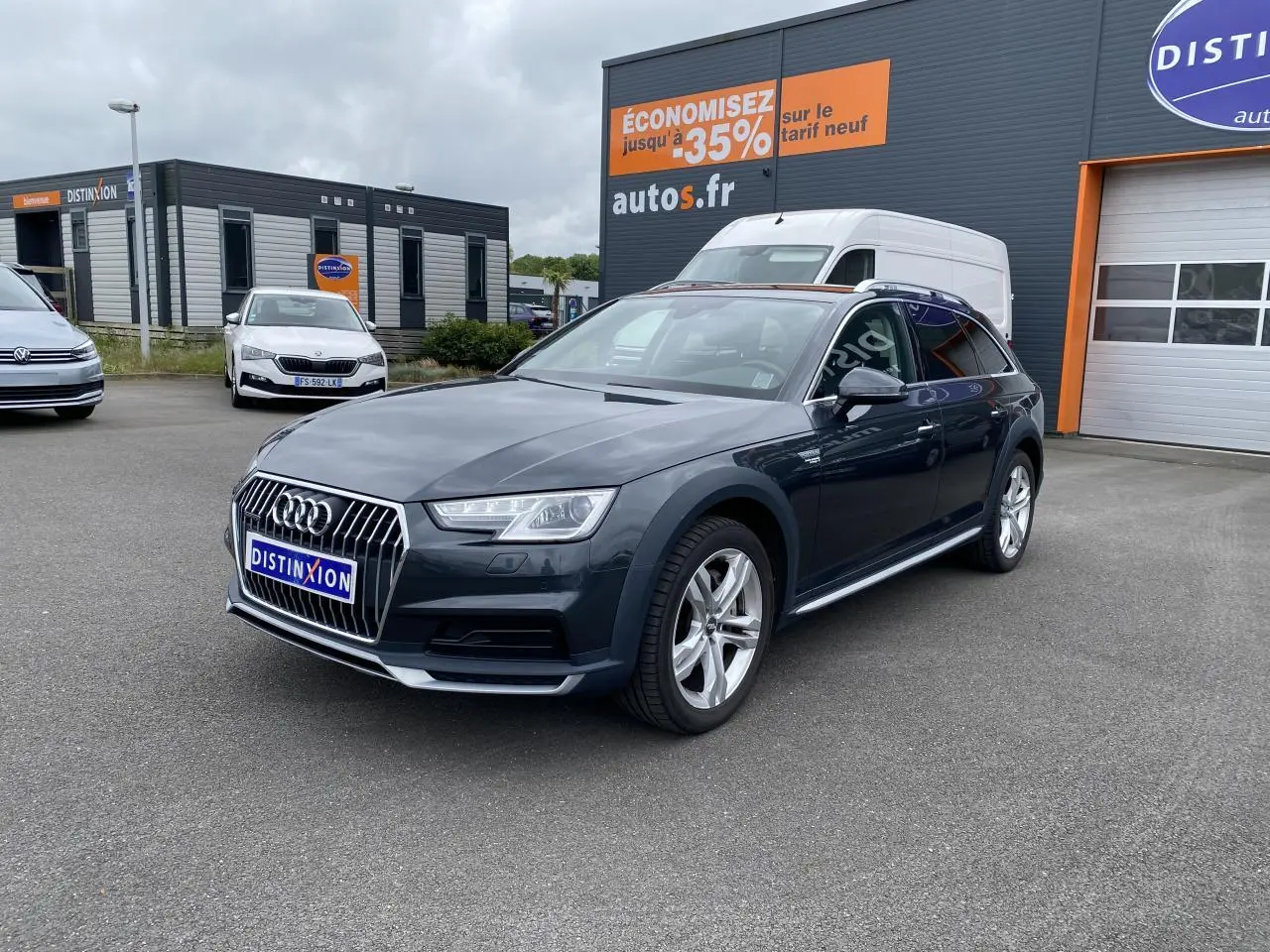 Audi A4 Allroad Quattro gris Manhattan en 3/4 avant droit, avec jantes aluminium 5 branches doubles visibles.