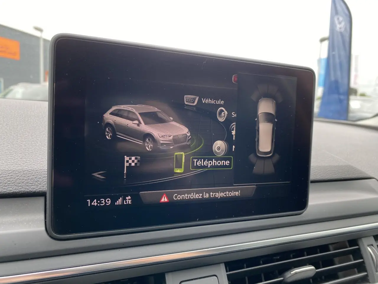 Écran central affichant une vue 3D grise de l'Audi A4 Allroad Quattro avec alertes de trajectoire et capteurs.