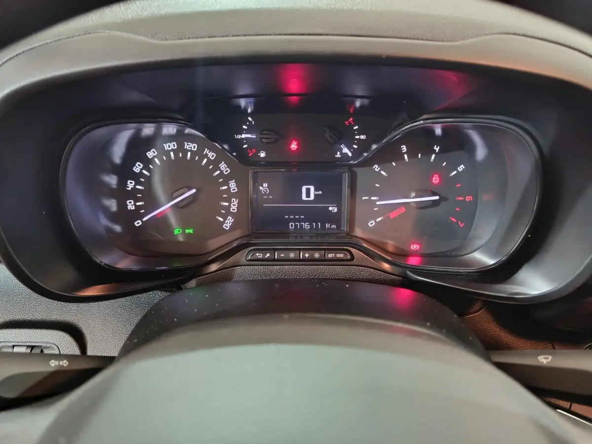 Vue rapprochée du tableau de bord noir du Citroën Berlingo 2021, affichant compteur et témoins lumineux allumés.