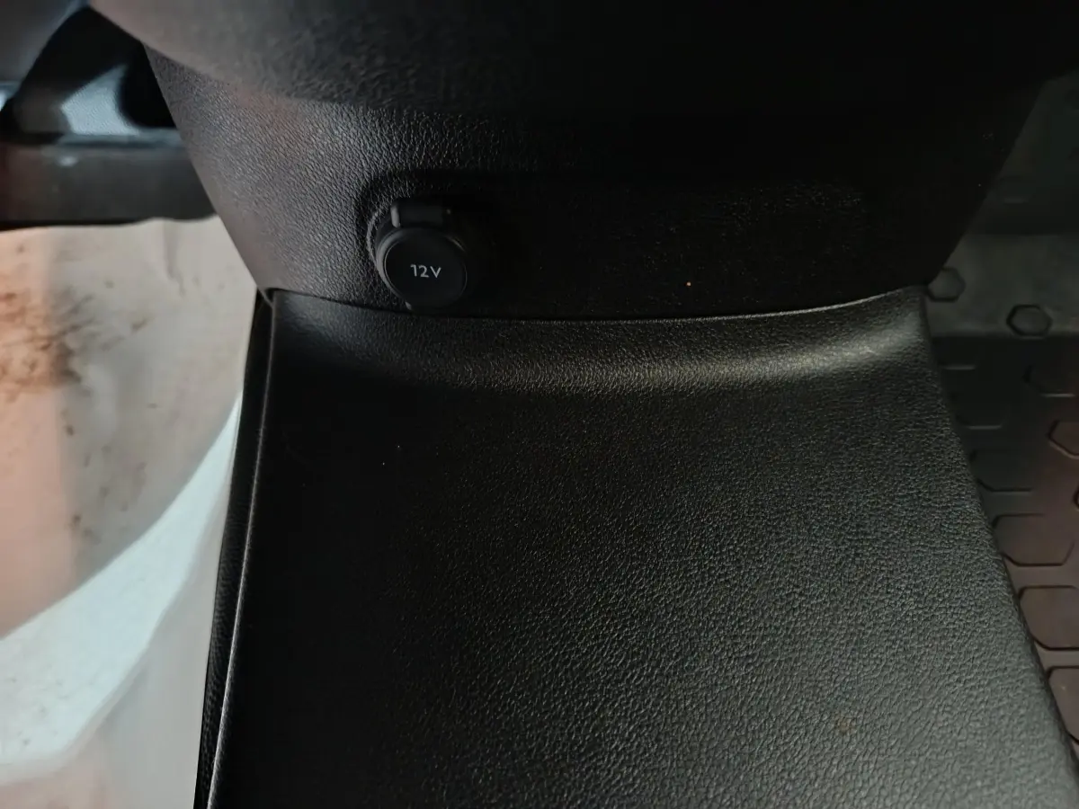 Gros plan sur la prise 12V noire située à la base de la console centrale d’un Citroën Berlingo blanc.