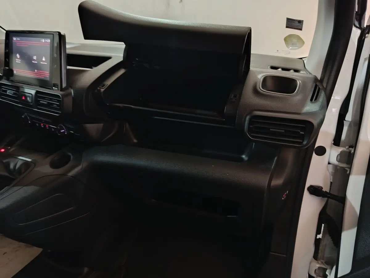 Vue intérieure côté passager du Citroën Berlingo blanc 2021, avec boîte à gants ouverte et tableau de bord noir.