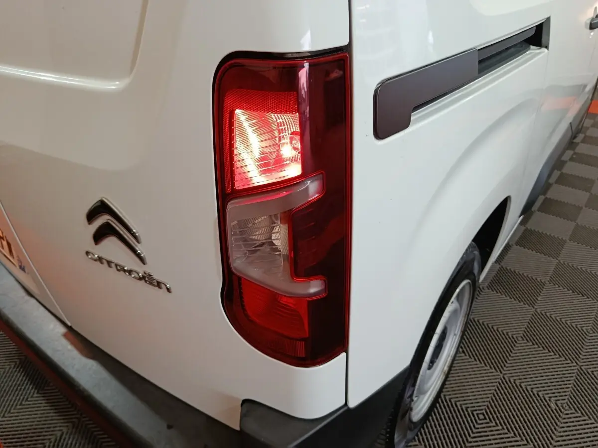 Feu arrière droit allumé sur Citroën Berlingo blanc, vue rapprochée du côté arrière droit du véhicule.
