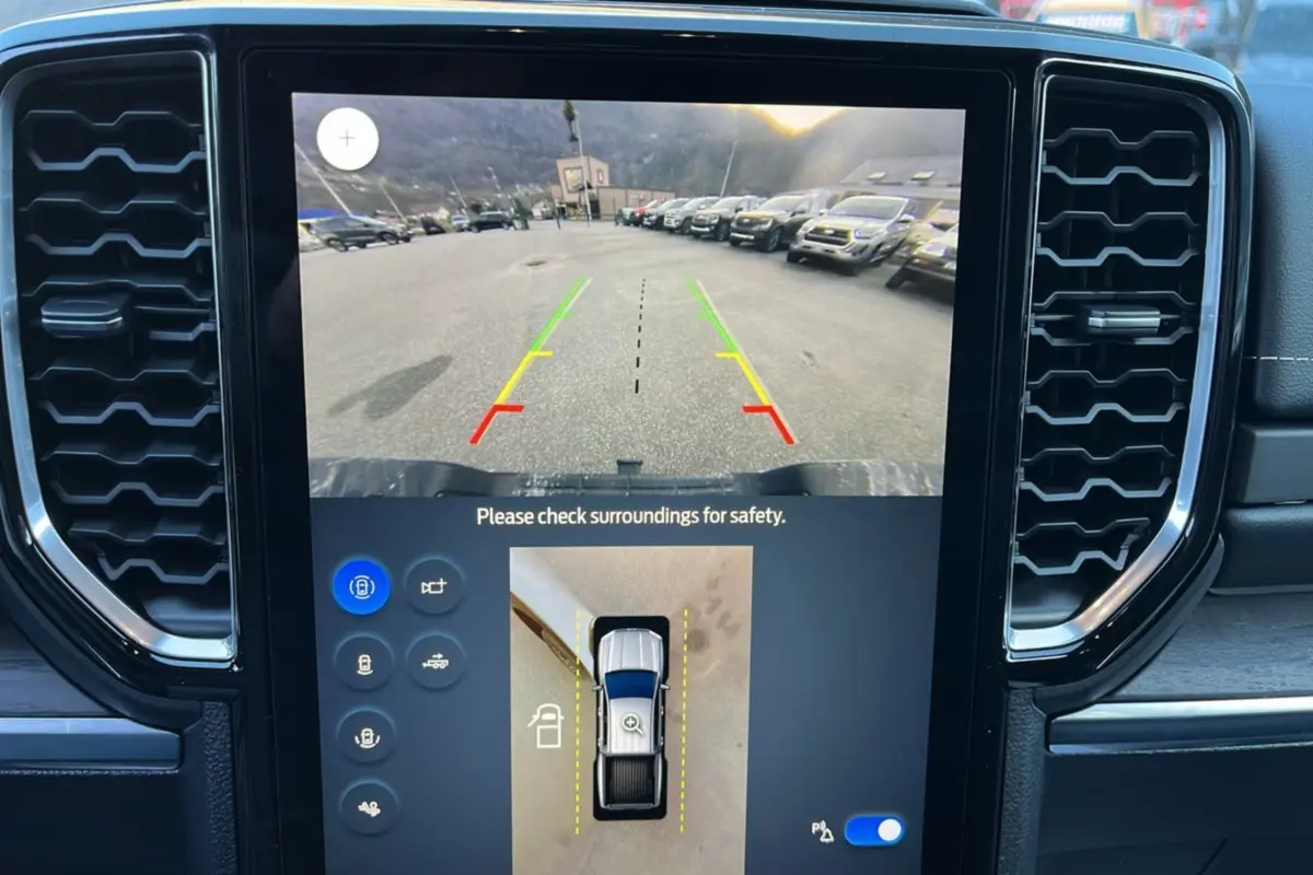 Vue intérieure du tableau de bord du Ford Ranger 2025, écran central affichant la caméra de recul et vue 360° du véhicule blanc glacier.
