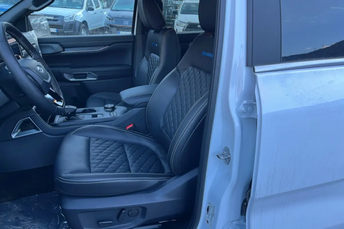 Vue intérieure côté conducteur du Ford Ranger blanc glacier 2025, sièges cuir noir matelassé avec surpiqûres blanches.