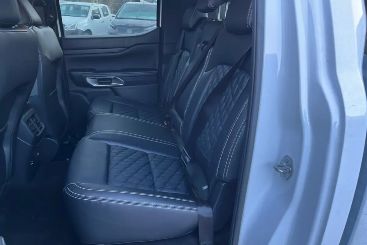 Vue côté droit arrière du Ford Ranger blanc glacier 2025, montrant les sièges arrière en cuir noir matelassé avec surpiqûres blanches.