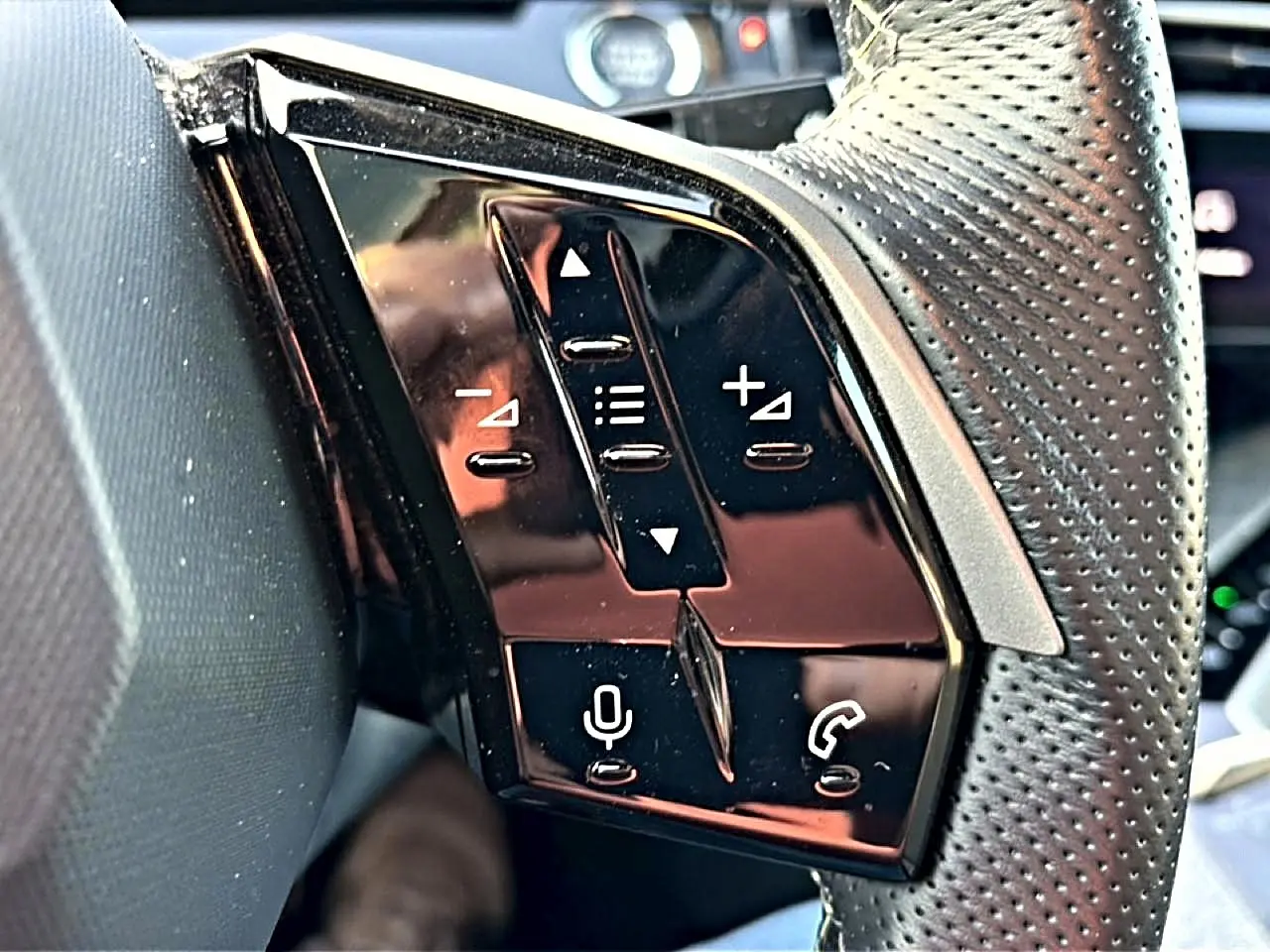 Gros plan sur les commandes vocales et téléphoniques sur le côté gauche du volant cuir perforé gris du Peugeot 3008.