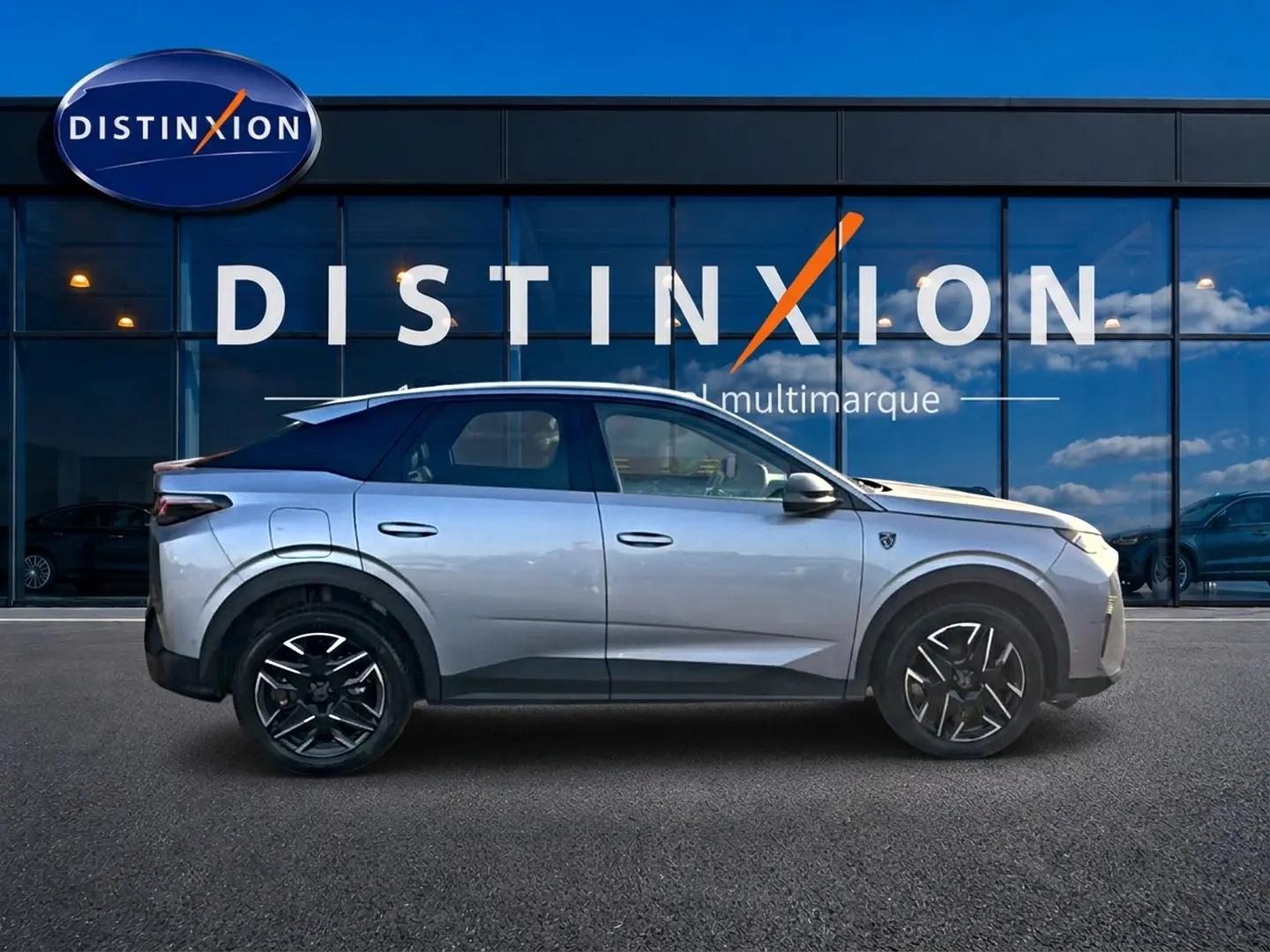 Peugeot 3008 gris en profil droit devant une vitrine avec logo Distinxion, jantes alliage noires visibles.