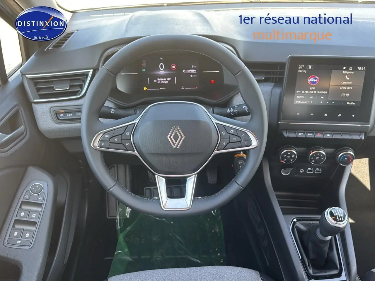 Vue intérieure centrée sur le volant multifonction et l’écran tactile de la Renault Clio V gris rafale, boîte manuelle visible.