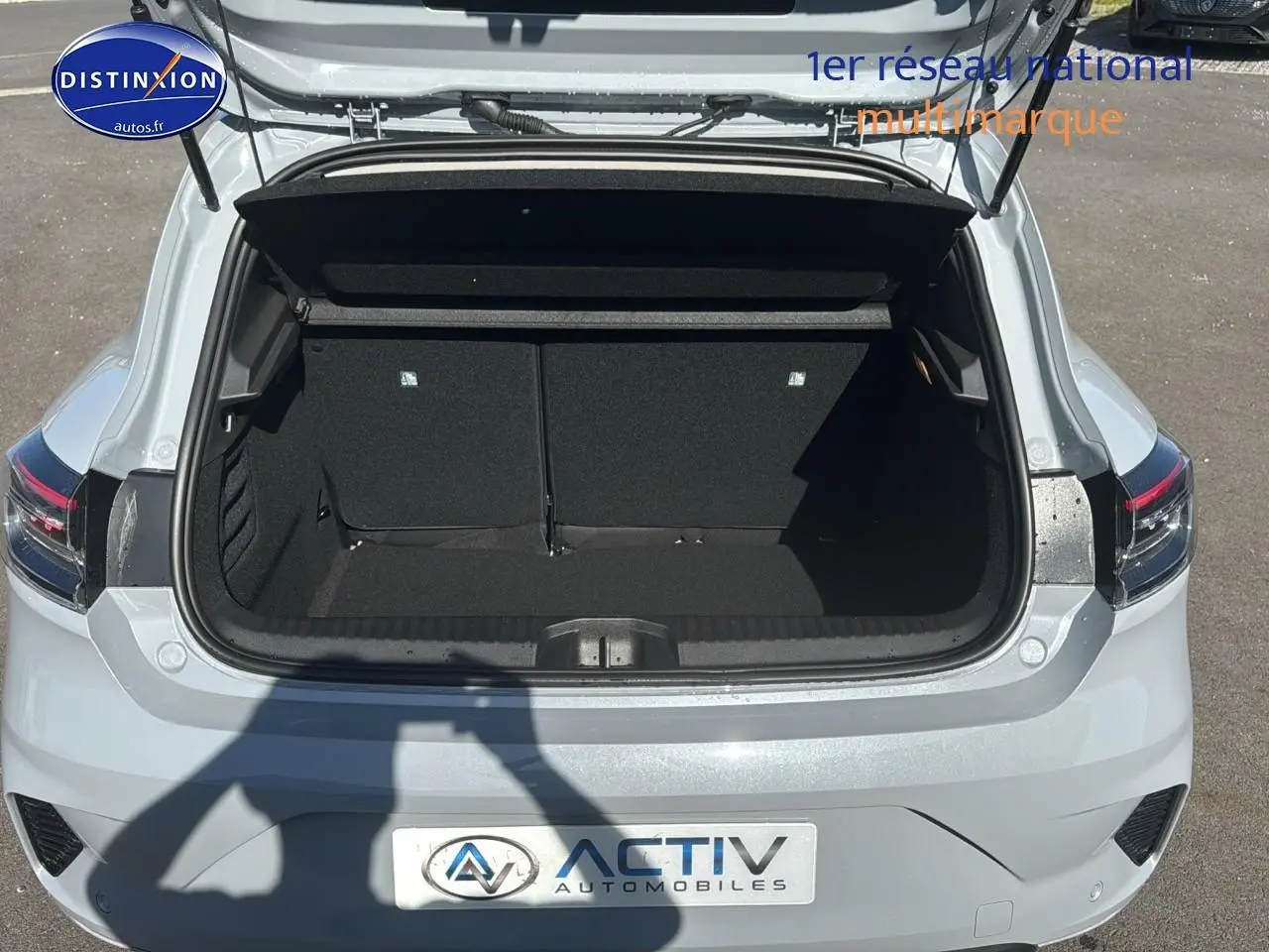 Coffre ouvert vu de l'arrière d'une Renault Clio V gris rafale, montrant l'espace de chargement vide.