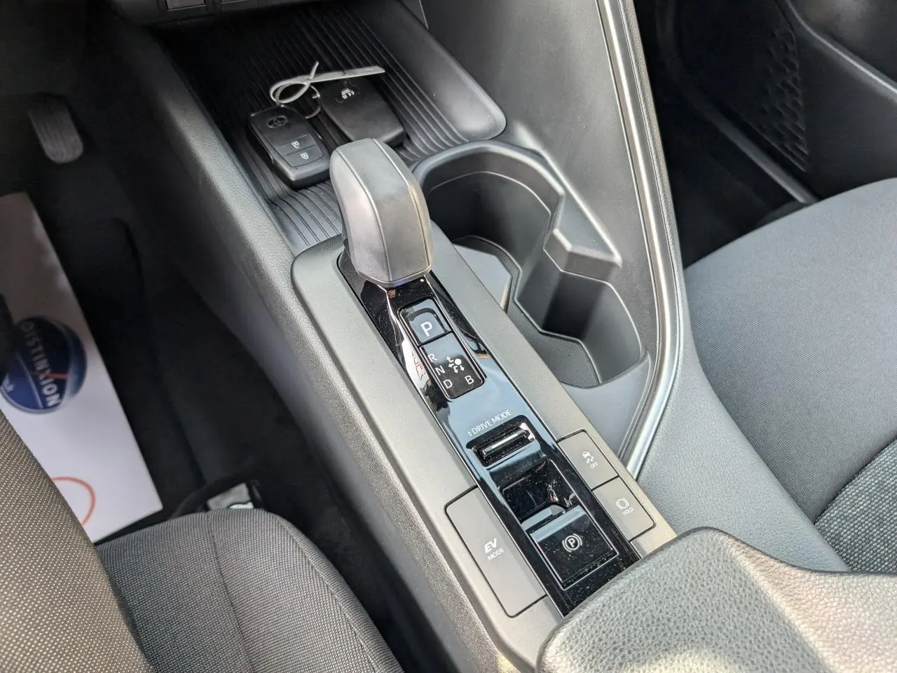 Vue rapprochée de la console centrale du Toyota C-HR blanc 2024, montrant le levier de vitesse automatique et les commandes hybrides.