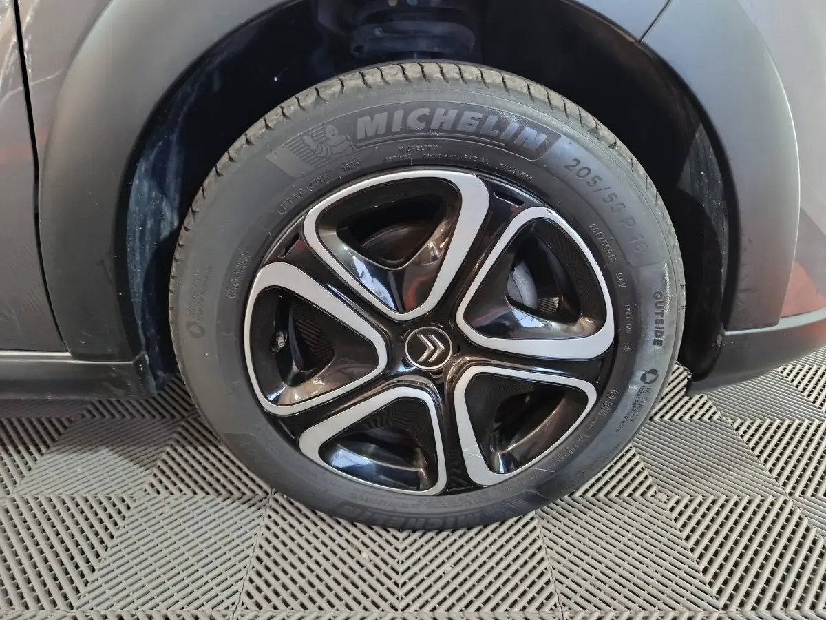 Gros plan sur la roue avant droite d'une Citroën C3 gris foncé avec jante alliage noire et argentée, pneu Michelin.