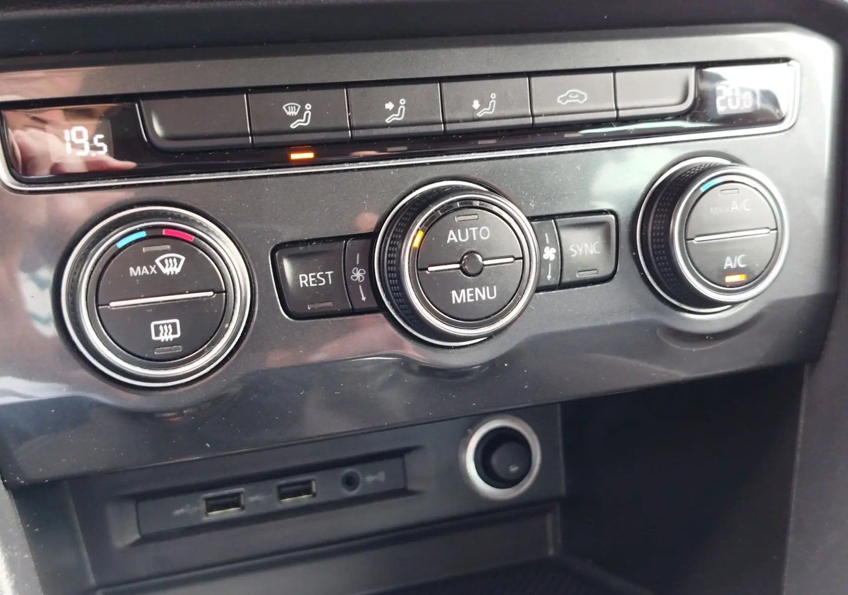 Vue rapprochée de la console centrale du Volkswagen Tiguan 2019 noir, montrant les commandes de climatisation et ports USB.
