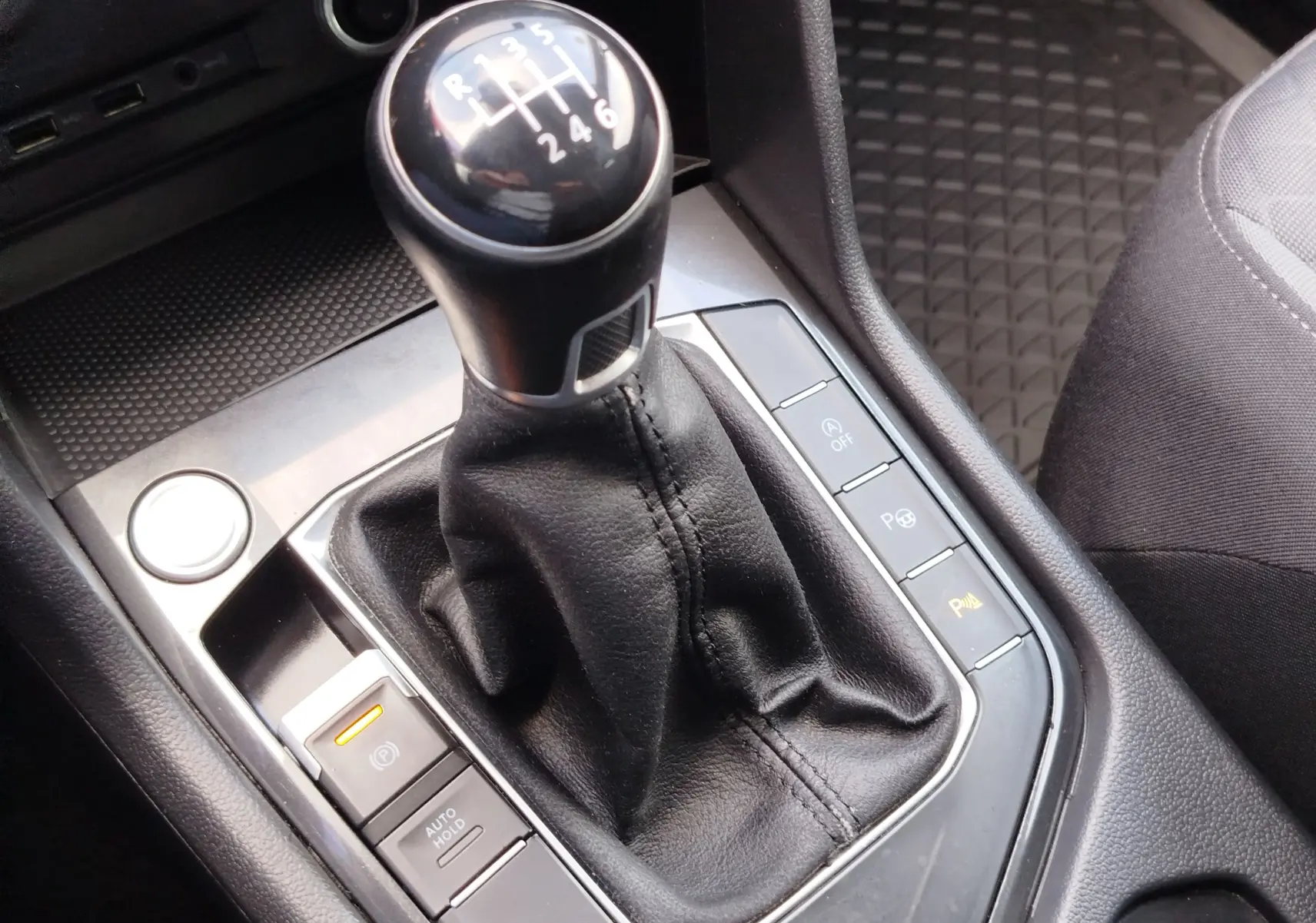 Le levier de vitesses manuel noir du Volkswagen Tiguan 2.0 TDI 2019, entouré de commandes et d’un revêtement en cuir noir.