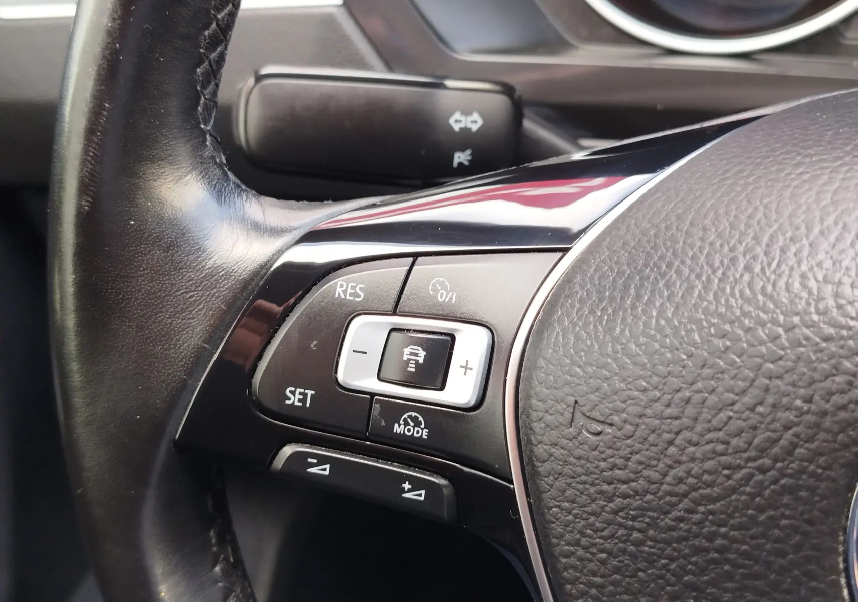 Gros plan sur les commandes du volant noir du Volkswagen Tiguan 2019, boutons de régulateur de vitesse visibles.