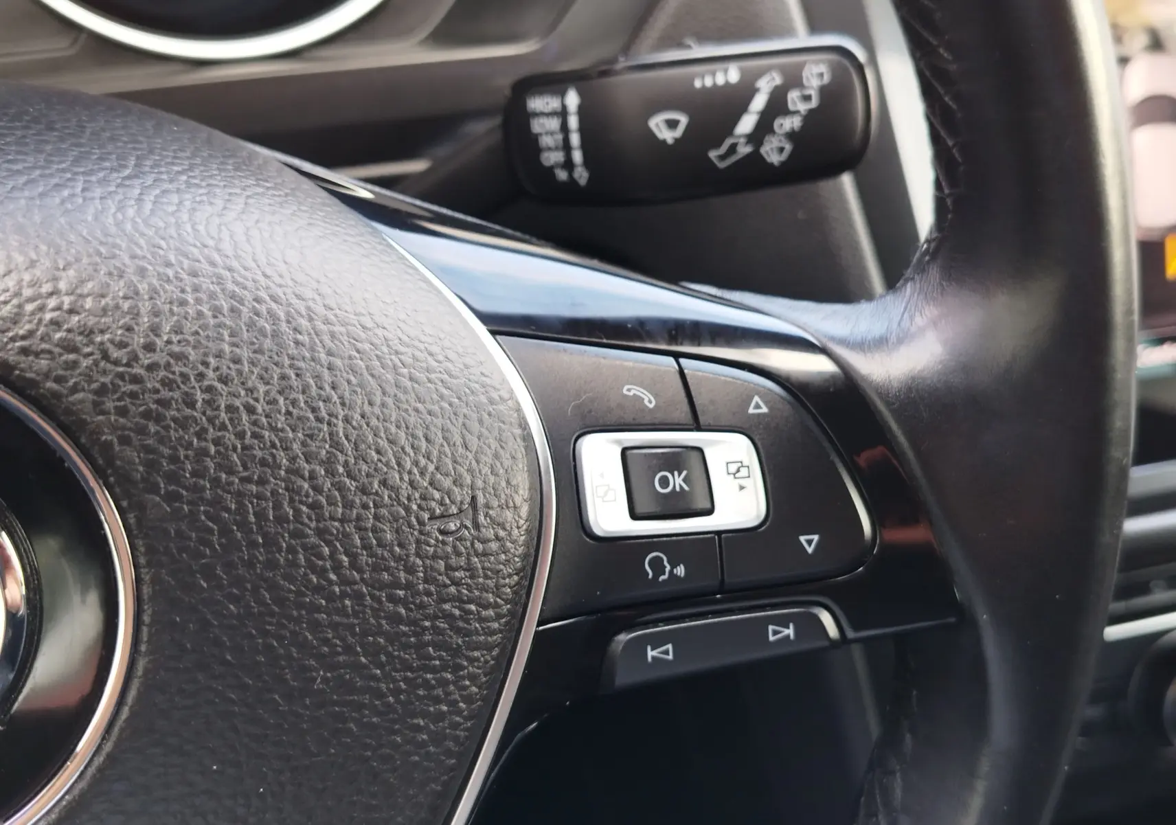 Gros plan sur les commandes multifonctions à droite du volant noir du Volkswagen Tiguan 2019, avec levier de commande en arrière-plan.