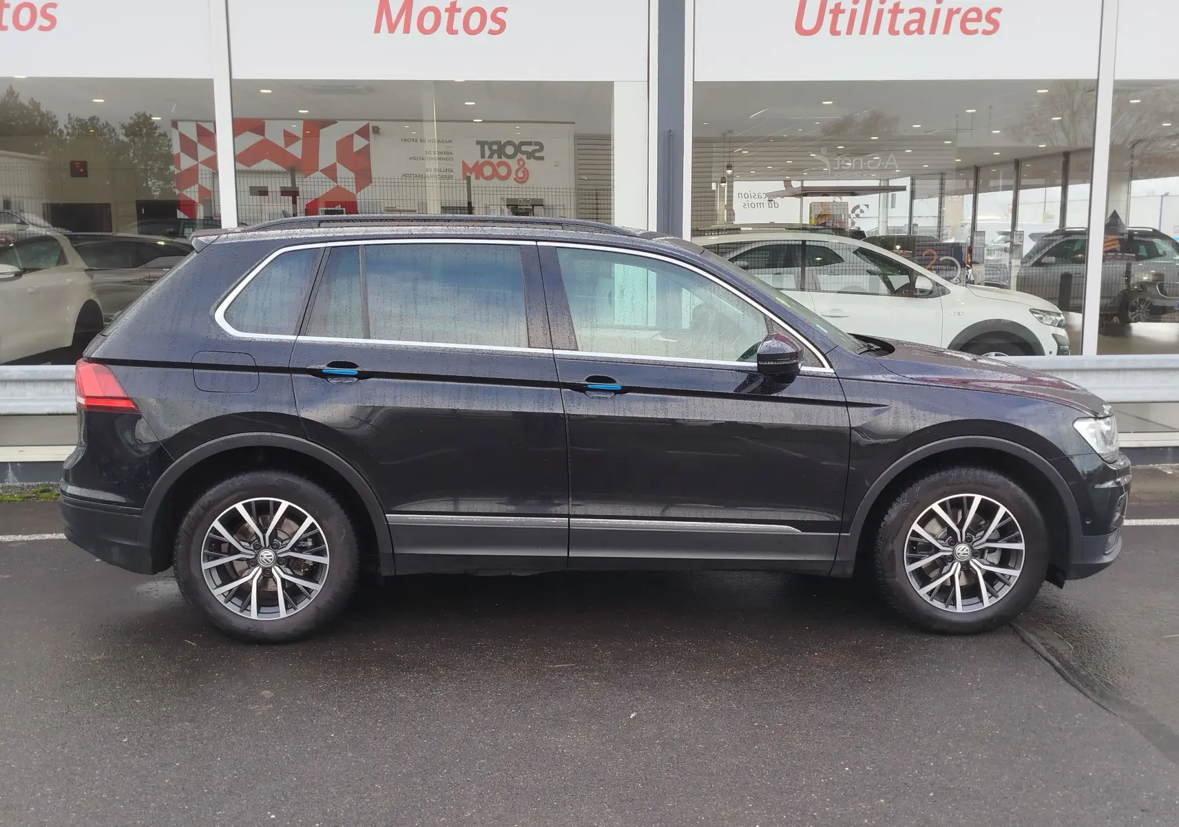 Vue de profil côté gauche d'un Volkswagen Tiguan 2.0 TDI noir intense nacré, avec jantes alliage et vitres teintées.