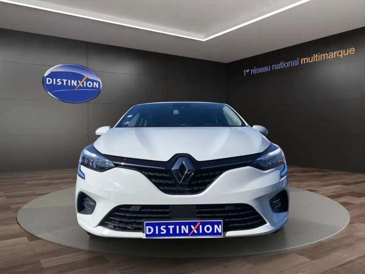 Vue avant d'une Renault Clio Business Réversible E-TECH 140 blanche, avec calandre noire et phares LED allumés.