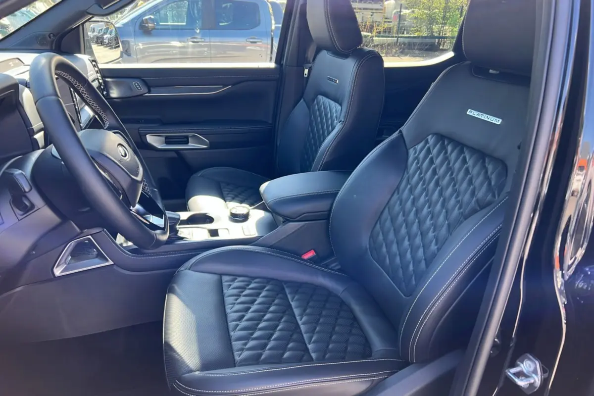 Vue intérieure côté conducteur du Ford Ranger 3.0 V6 Platinum avec sièges cuir noirs matelassés et volant multifonctions.