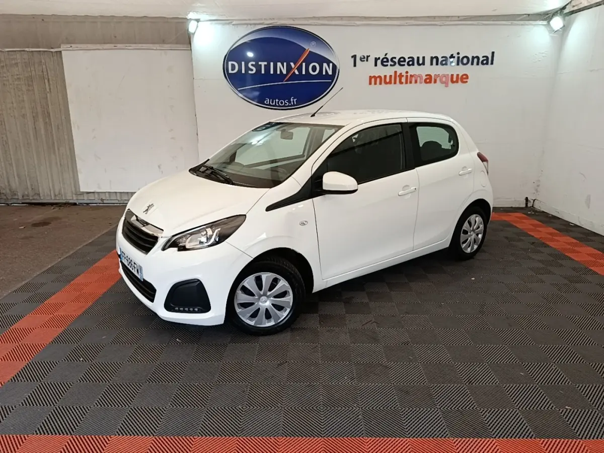 Peugeot 108 blanc vue 3/4 avant droit dans un showroom avec logo Distinxion en arrière-plan.