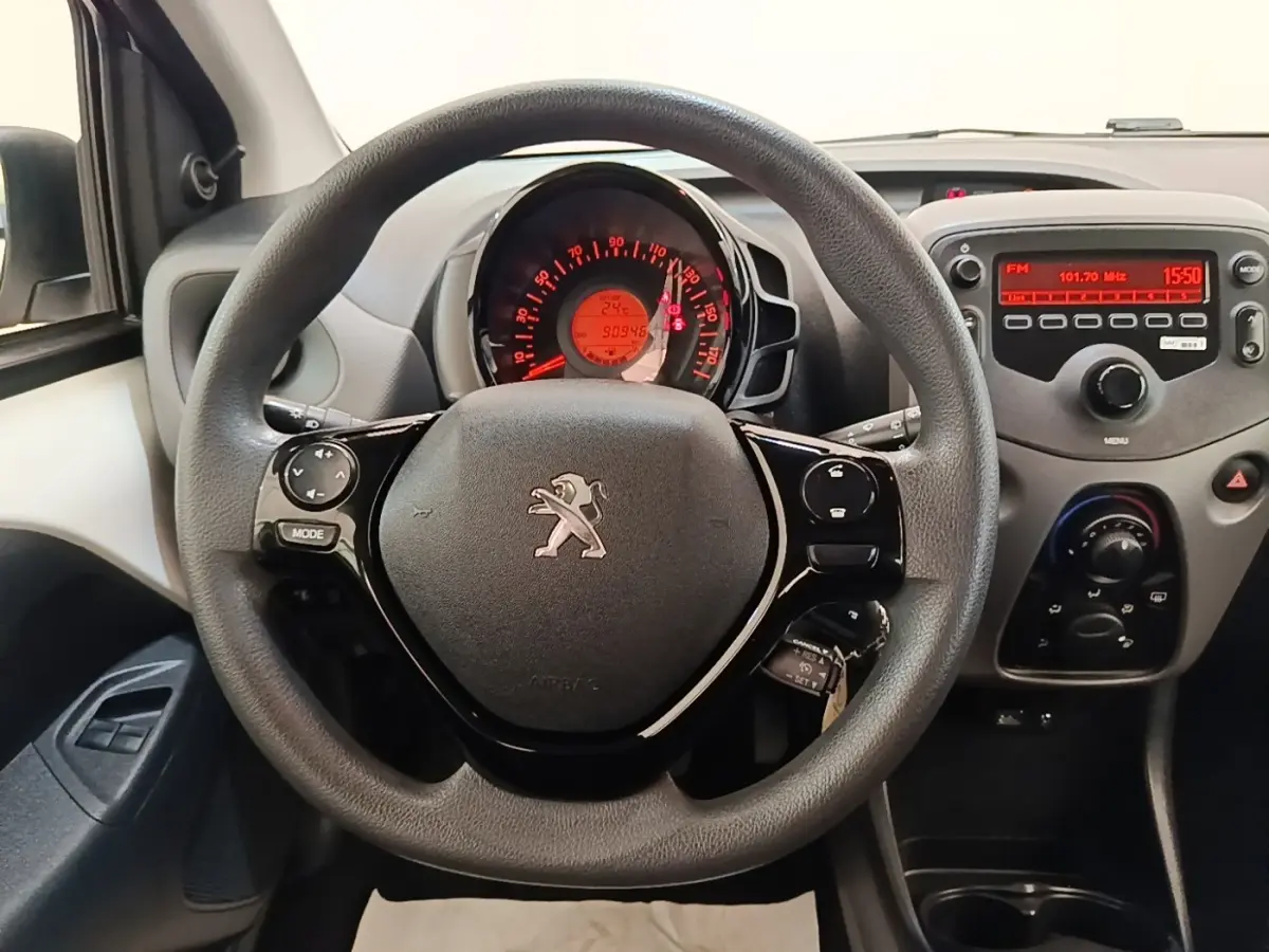 Vue intérieure centrée sur le volant multi-fonctions noir de la Peugeot 108 blanche avec tableau de bord et console radio.