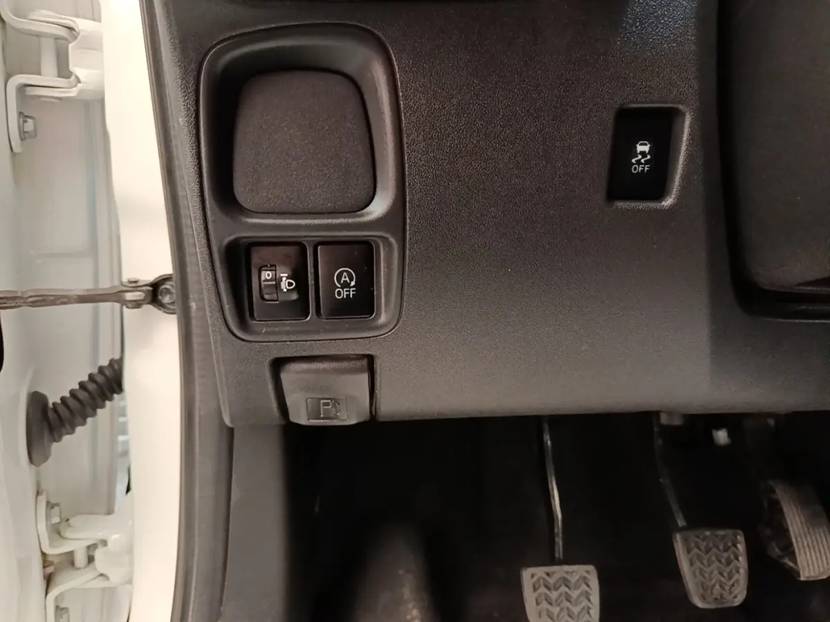 Vue rapprochée des commandes sous le tableau de bord côté conducteur d’une Peugeot 108 blanche, 2020.